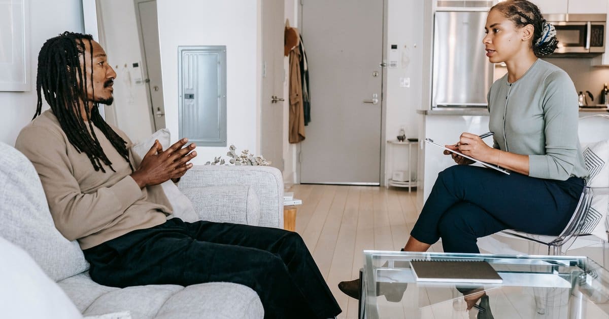 A therapist and client sitting across from each other in a warmly lit counseling office during a session