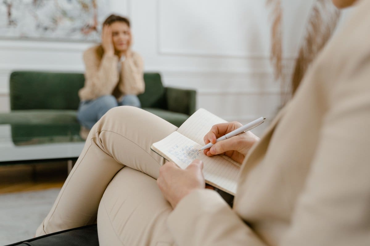 A counselor taking notes on a clipboard during a one-on-one therapy session