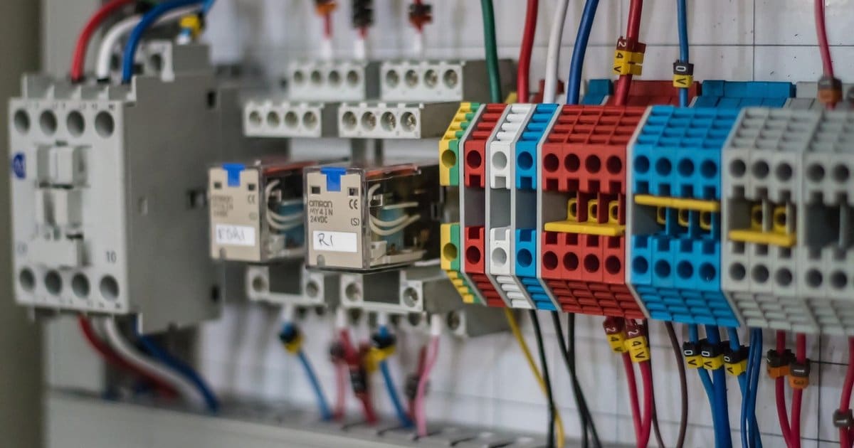 An electrician's hands wiring an open electrical panel, illustrating hands-on trade work for a career-change audience