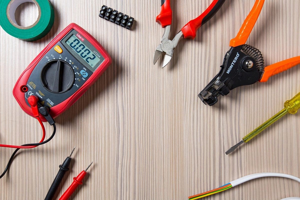 An electrician's hand tools laid out for a repair job, including testers and wire cutters