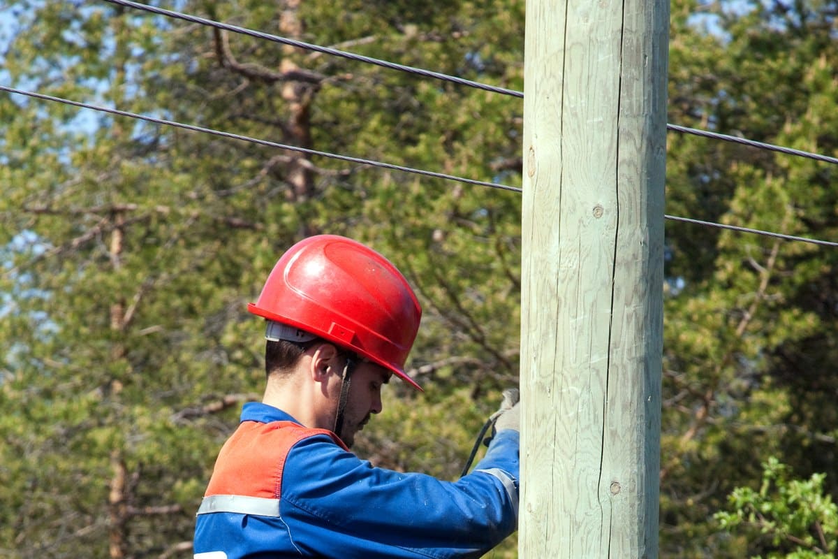 An electrical trades worker in safety gear performing hands-on work outdoors